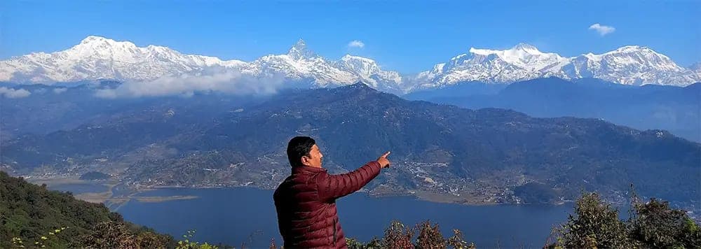 Yogi Panchavedi pointing toward the Annapurna range above Phewa Lake
