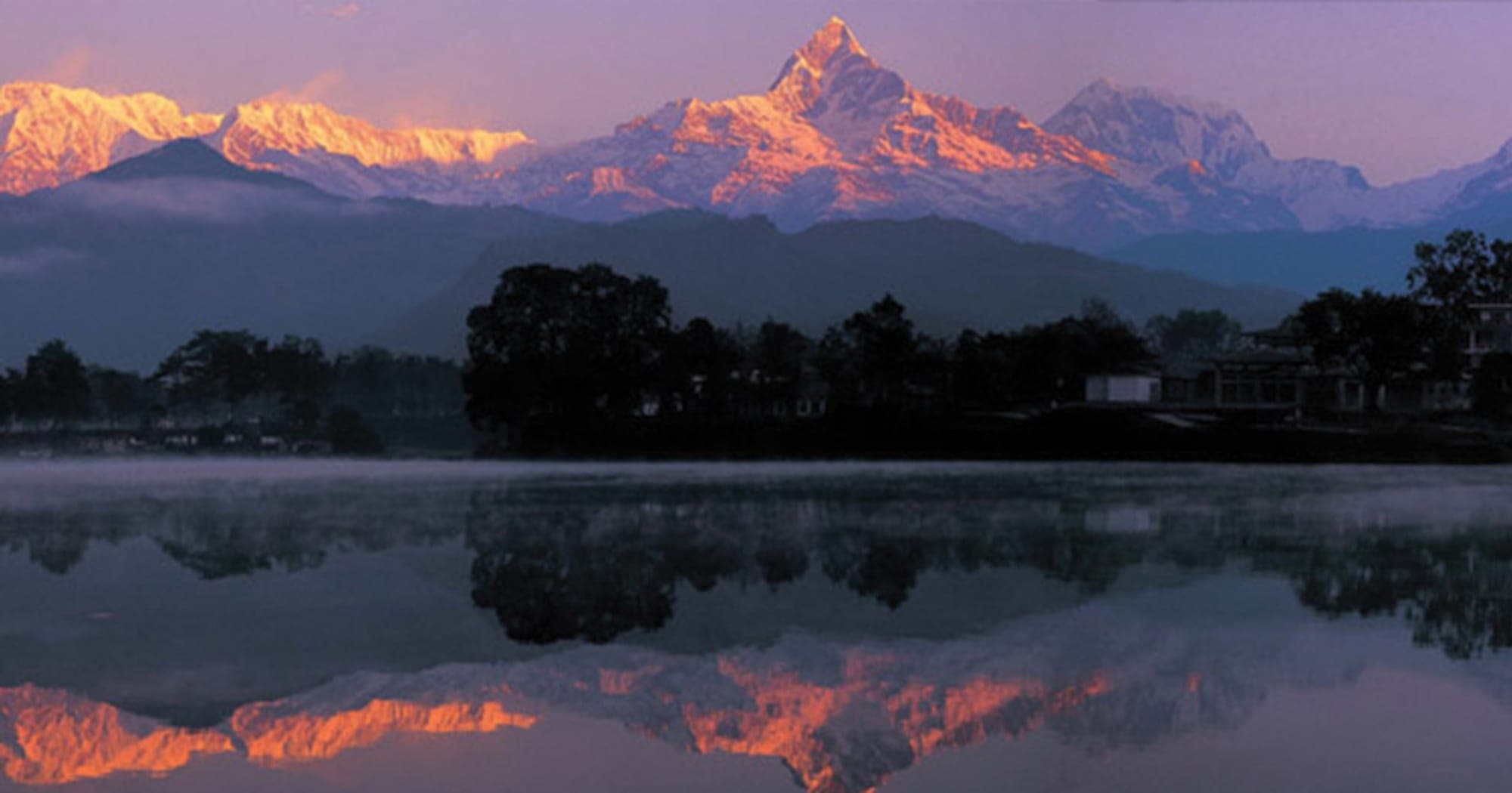 Machhapuchhre reflected in still lake water at dawn