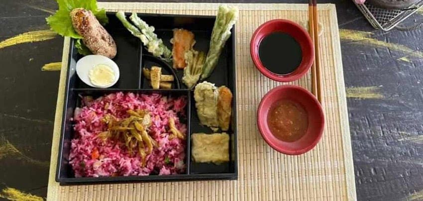 An Ayurvedic bento box of coloured rice, pickles and tempura vegetables