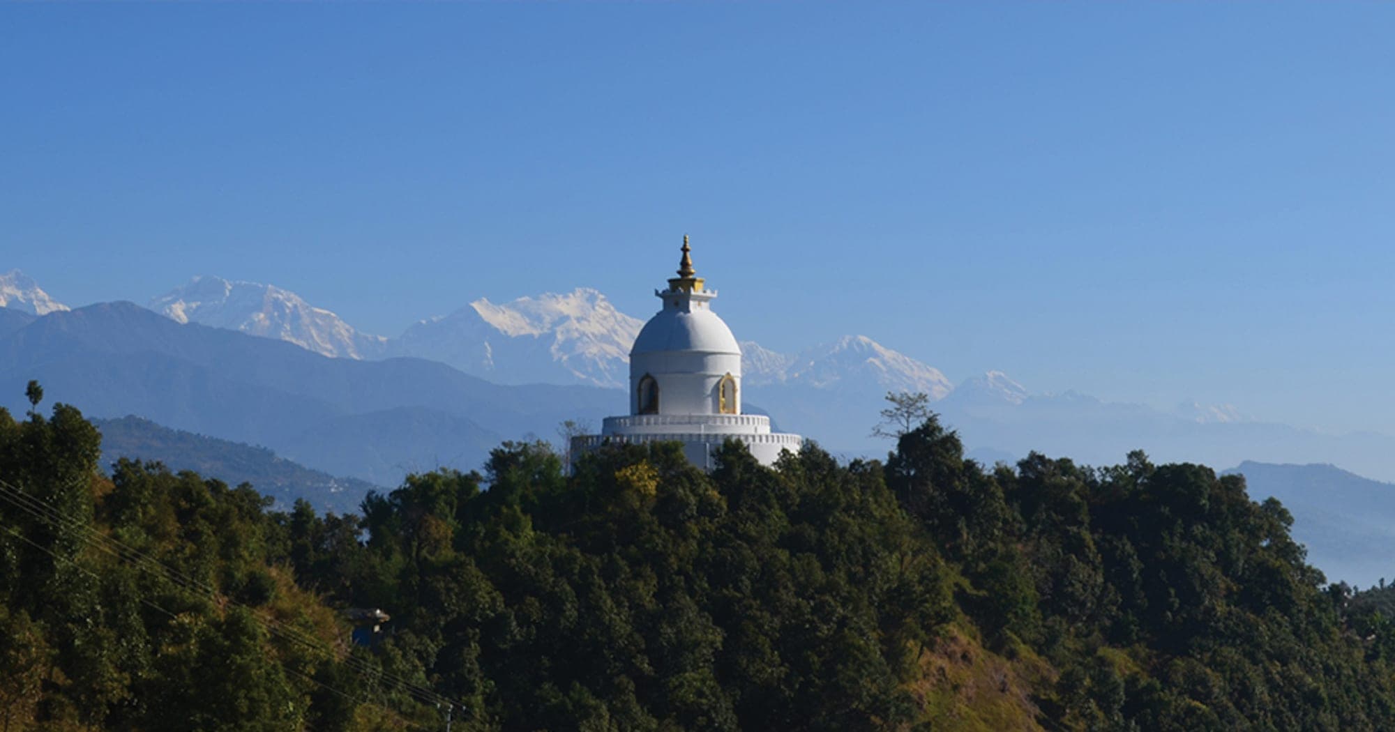 The World Peace Stupa on its ridge with the Annapurna range behind