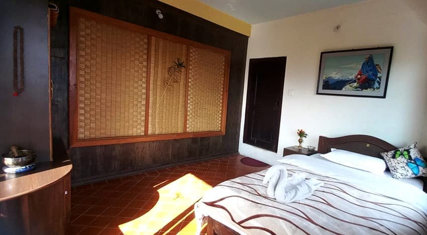 A guest room with woven panelling, warm parquet and a made bed